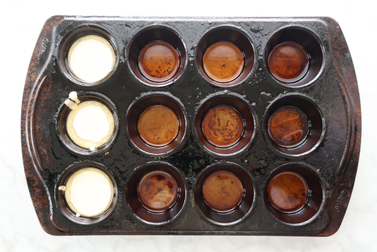 Filling hot tins with Yorkshire Pudding batter. You can see the oil in the bottom of the tins and it covering the top of the batter.