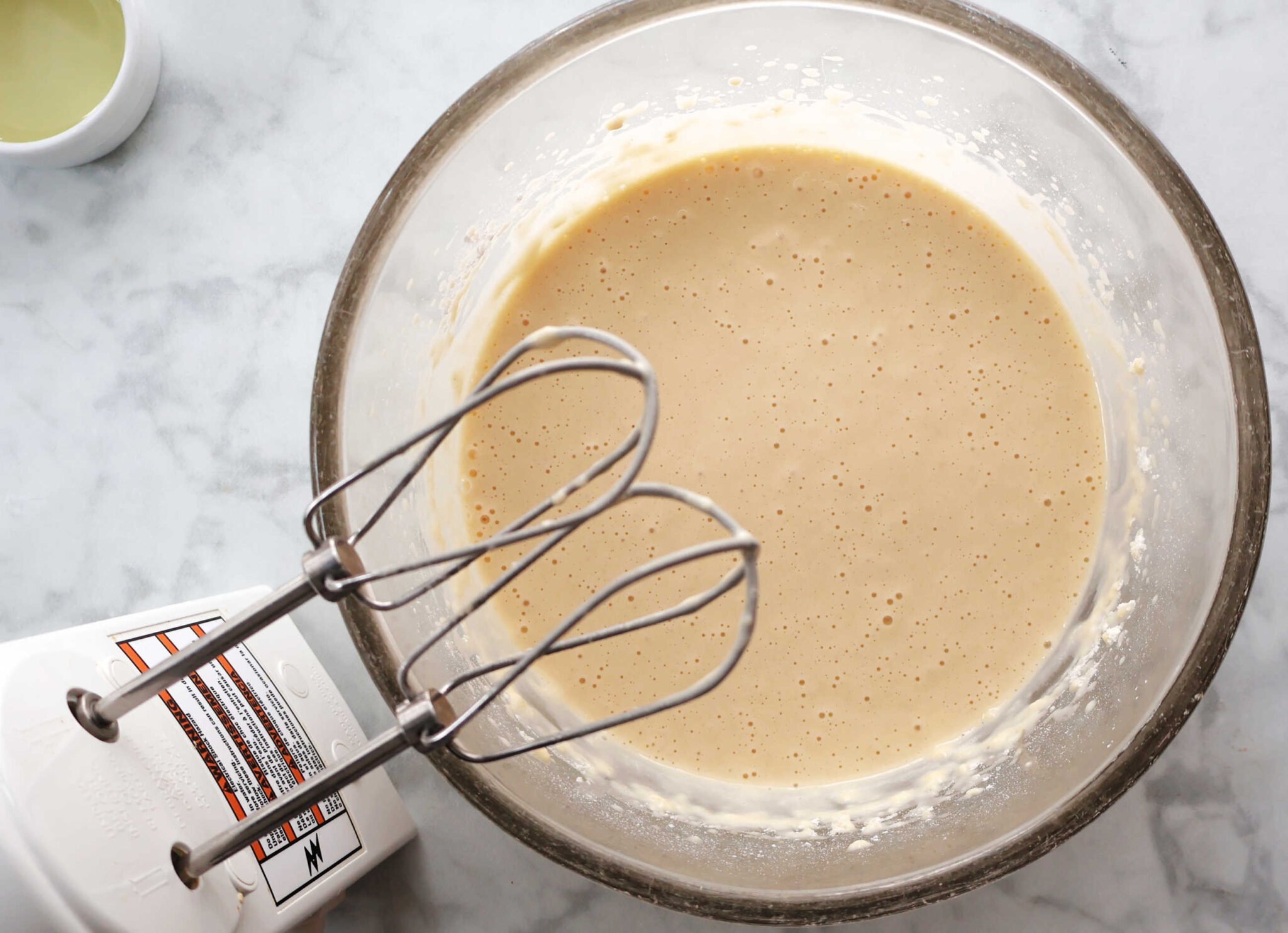 Ingredients for Yorkshire Pudding combined with a hand mixer. The batter is very liquid.