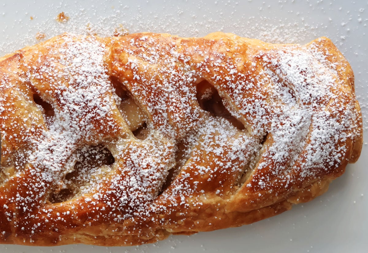 Apple strudel pastry with slits so you can see the delicious apples inside. A sprinkle of icing sugar on top to decorate.