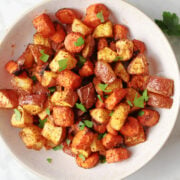 air fried carrots and red potatoes in a white bowl. This side dish is seasoned with smoked paprika adding to the color and flavor.