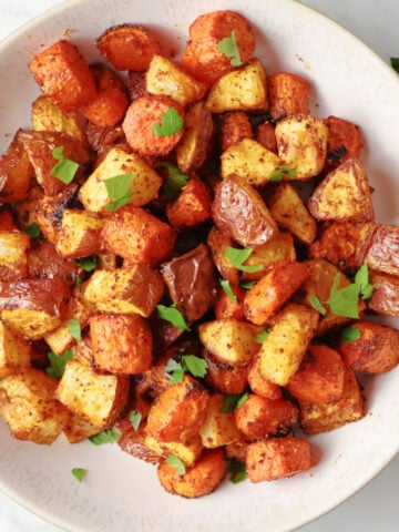 air fried carrots and red potatoes in a white bowl. This side dish is seasoned with smoked paprika adding to the color and flavor.