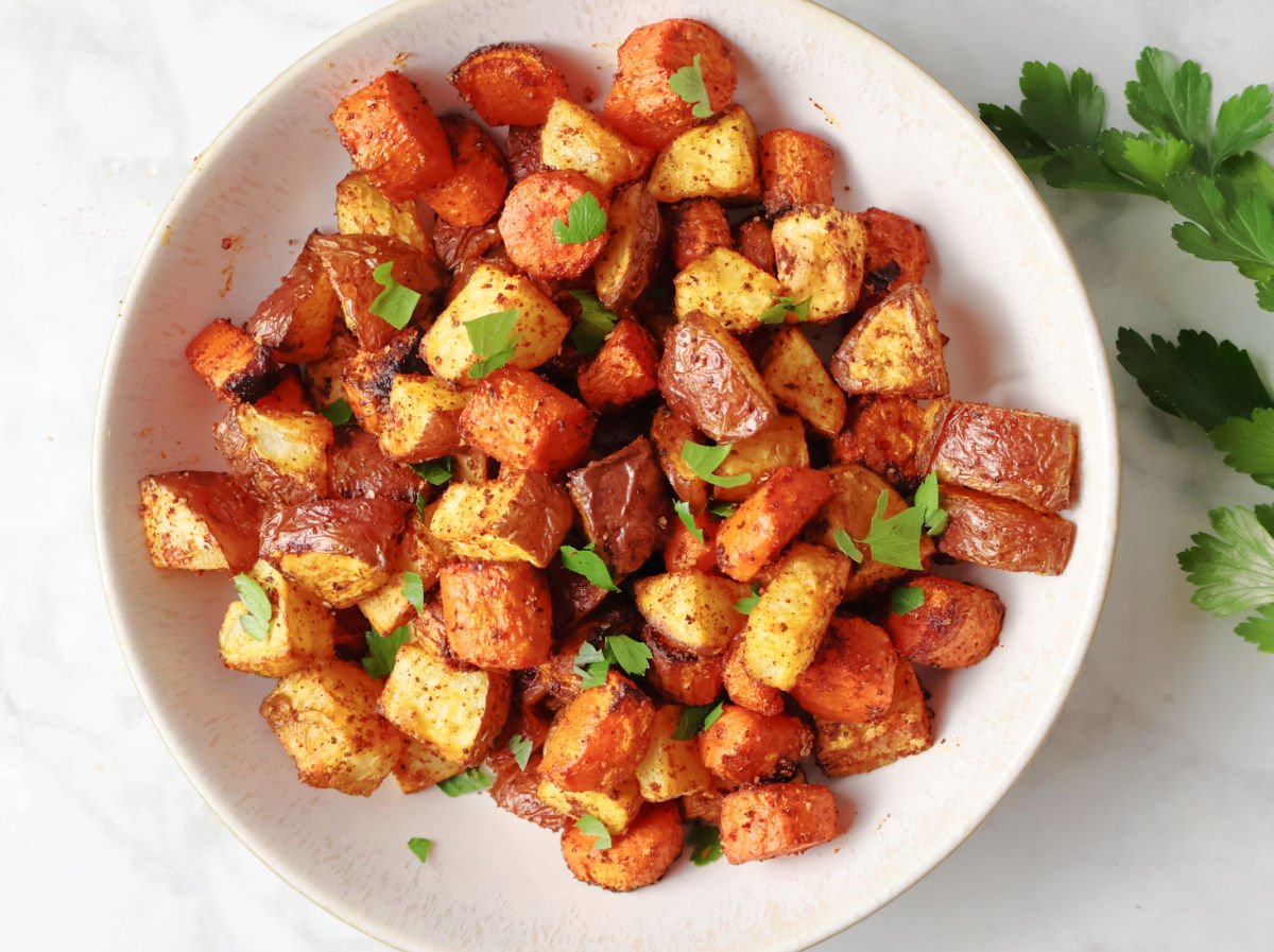 air fried carrots and red potatoes in a white bowl.  This side dish is seasoned with smoked paprika adding to the color and flavor.