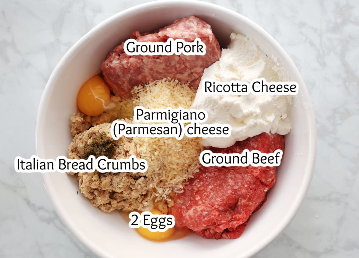 Ingredients for ricotta meatballs in a bowl. Ingredients include ground pork, ground beef, ricotta cheese, parmigiano cheese, Italian bread crumbs and eggs.