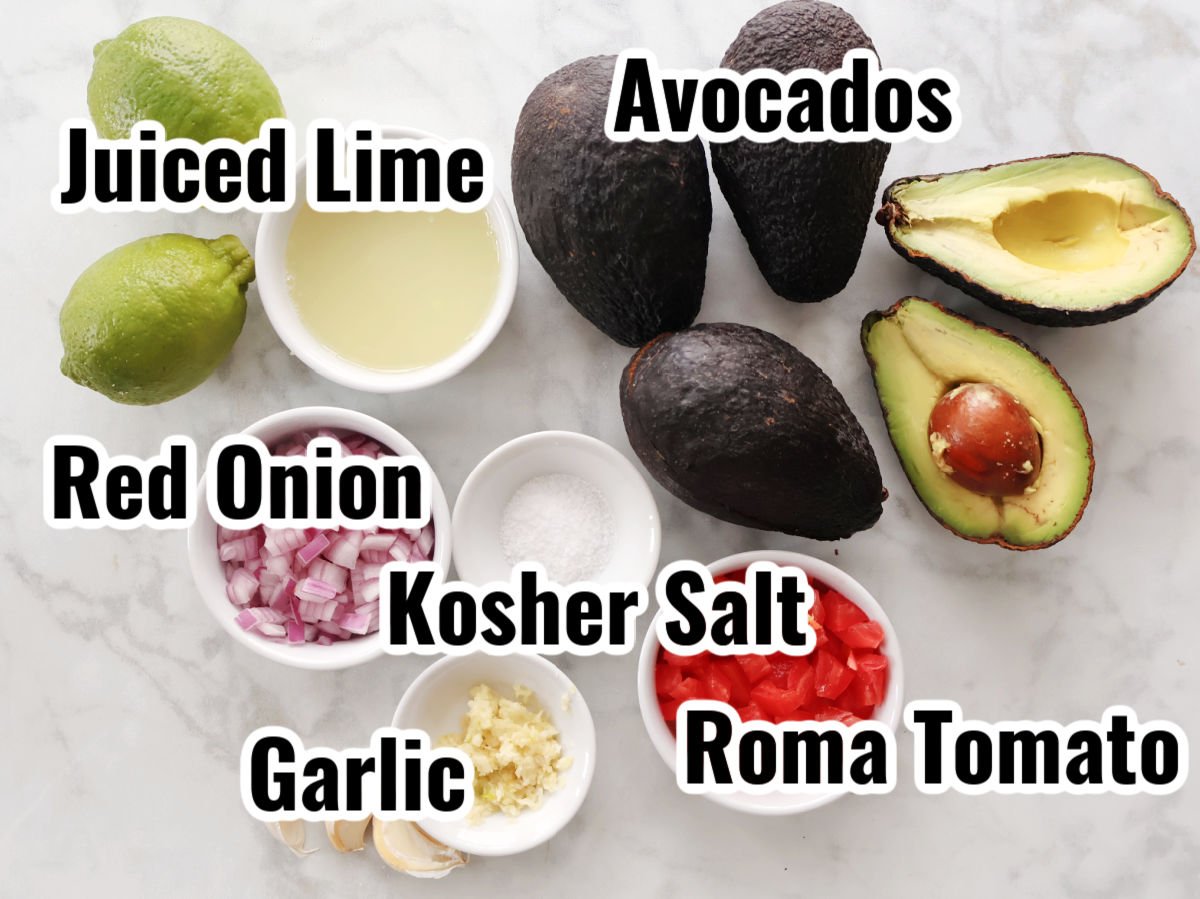 Ingredients for homemade duacamole including avocados, lime, diced onions and tomatoes, garlic and kosher salt.