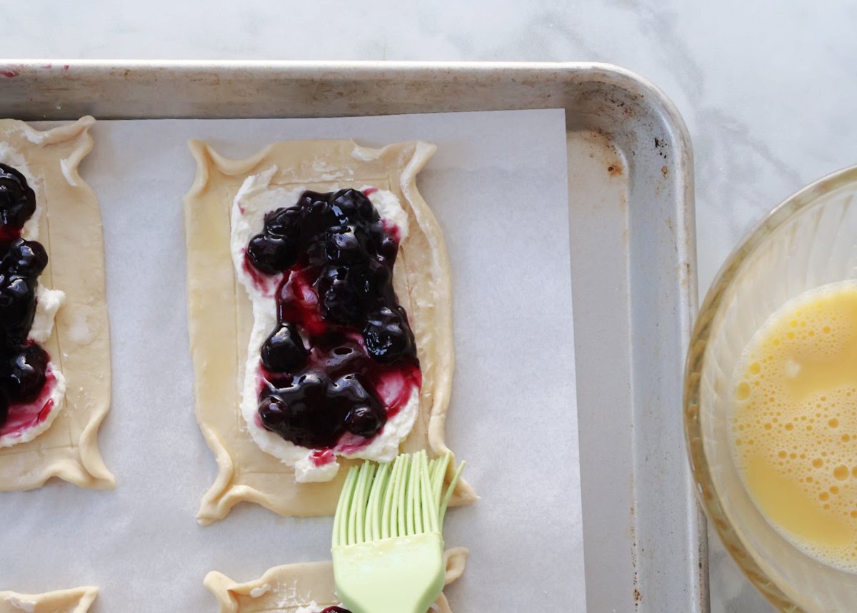 puff pastry with cream cheese as the first layer then blueberry filling as the second layer. Edges of the puff pastry are coated with an egg wash.