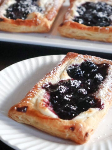 A blueberry cheese danish on a white plate.