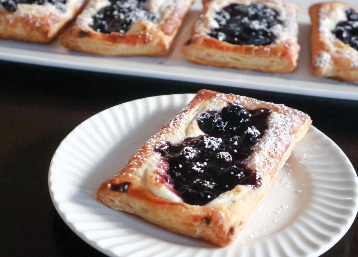 A blueberry cheese danish on a white plate.