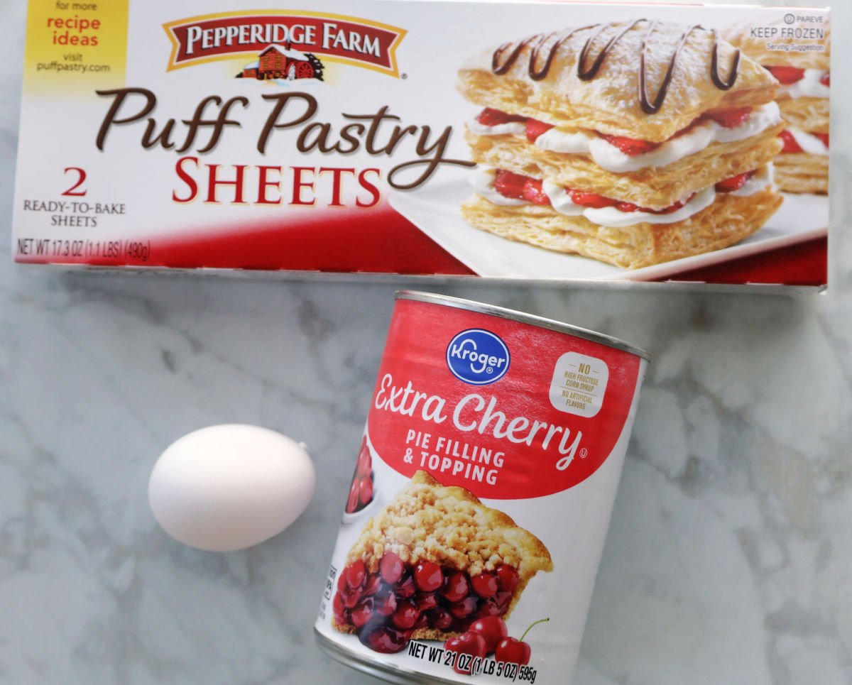 Ingredients for cherry danishes which include puff pastry, cherry pie filling and an optional egg for the egg wash.