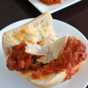 sub meatball with melted cheese and marinara sauce on a white plate.