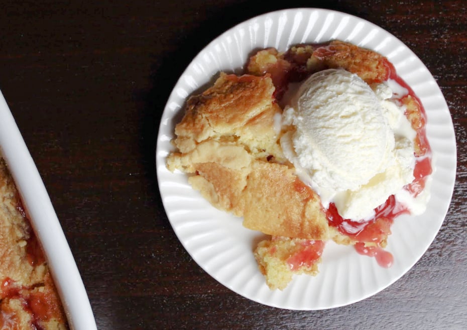 cherry pineapple dump cake served on a white plate with a scoop of ice cream. 