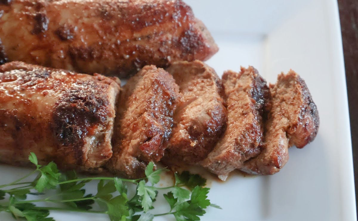 Sliced oven roasted tenderloin. It has a sugar caramelized crust and the pork slices are moist and tender .