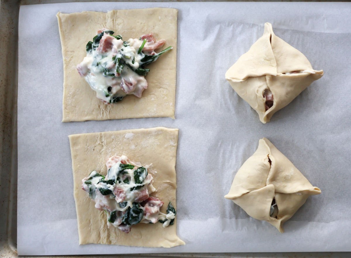 spooning ham, cheese and spinach mixture ont puff pastry squares.  Two puff pastry squares are folded up.