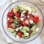 Final mixed Greek salad with chopped cucumbers, tomatoes, red onions, feta, and olives tossed in lemon oregano dressing.