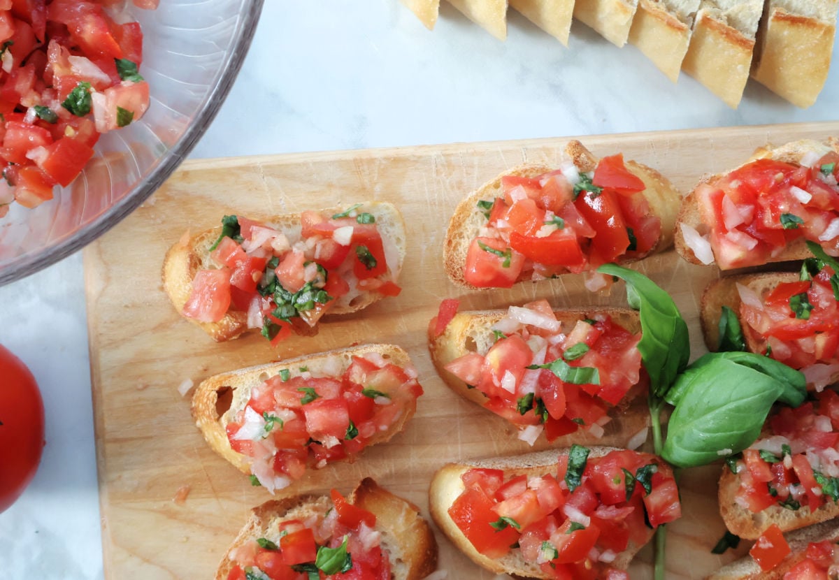 Toasted slices of baguette with bright red tomato topping, ready to be served as a summer appetizer