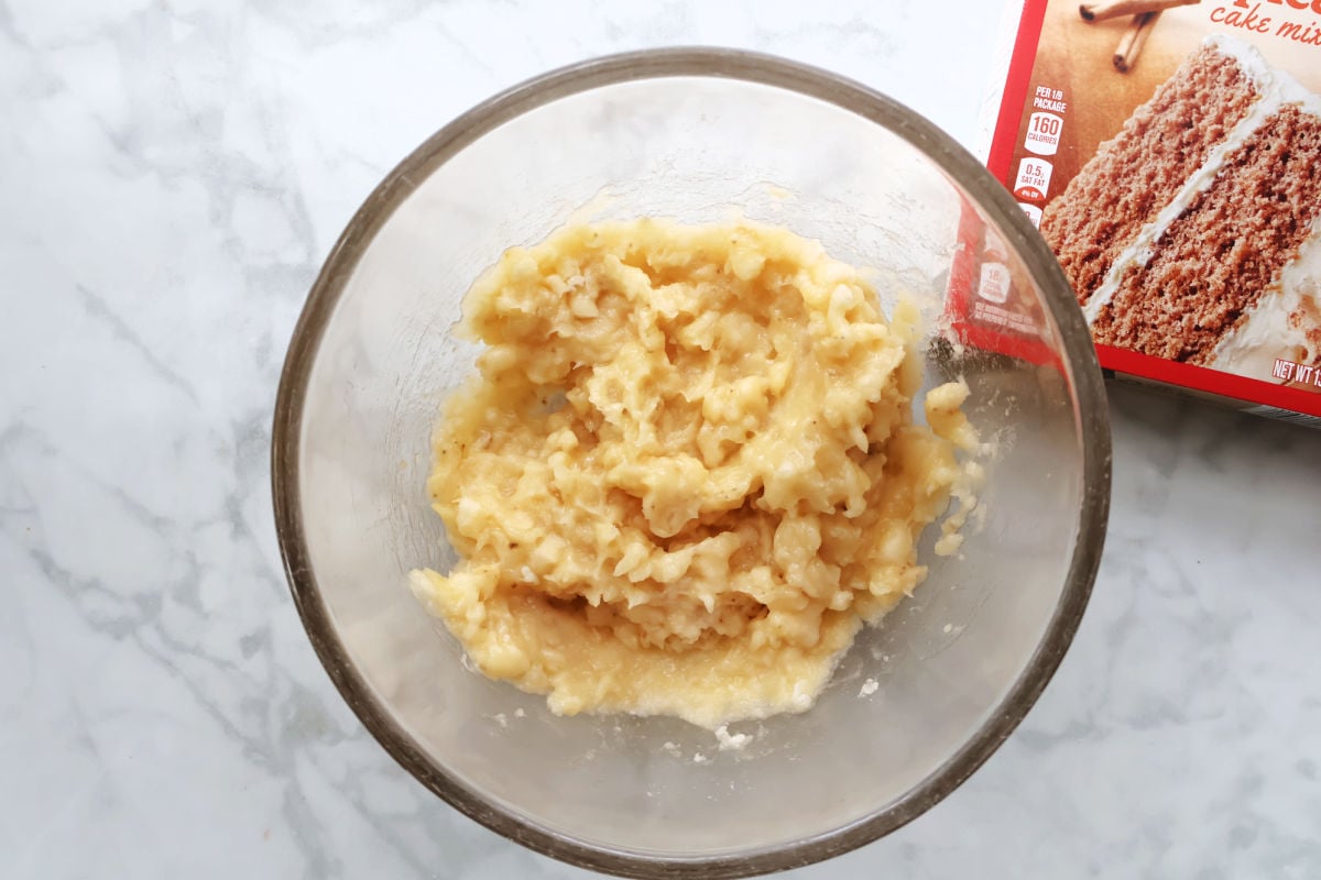 mashed bananas with some banana chunks in a clear glass bowl.