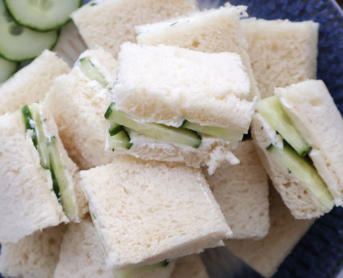Cucumber sandwiches arranged on white plate with crusts removed