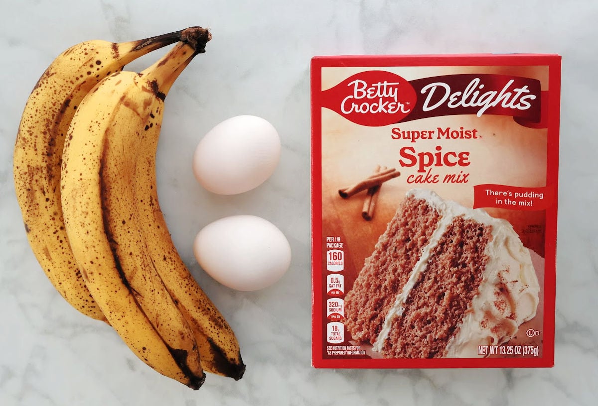 three ingredient banana bread ingredients on a counter. Ingredients are 3 overripe bananas, 2 large eggs and some spice cake.