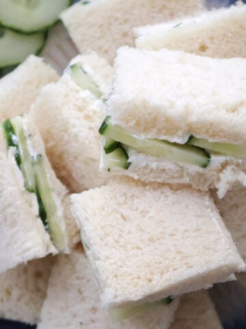 Cucumber sandwiches arranged on white plate with crusts removed
