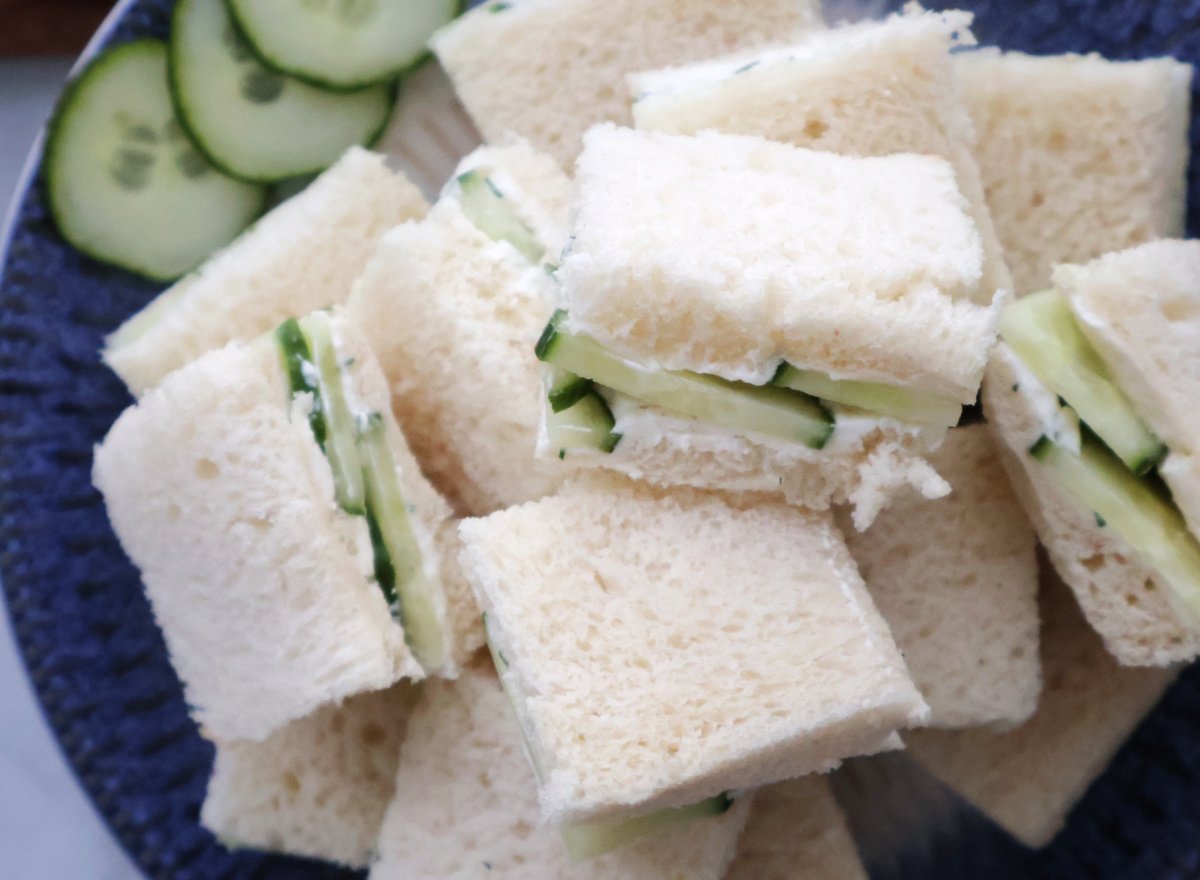 Cucumber sandwiches arranged on white plate with crusts removed