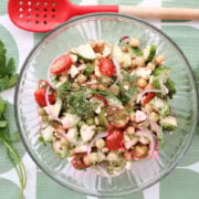 Cucumber chickpea salad garnished with fresh dill and parsley sprigs