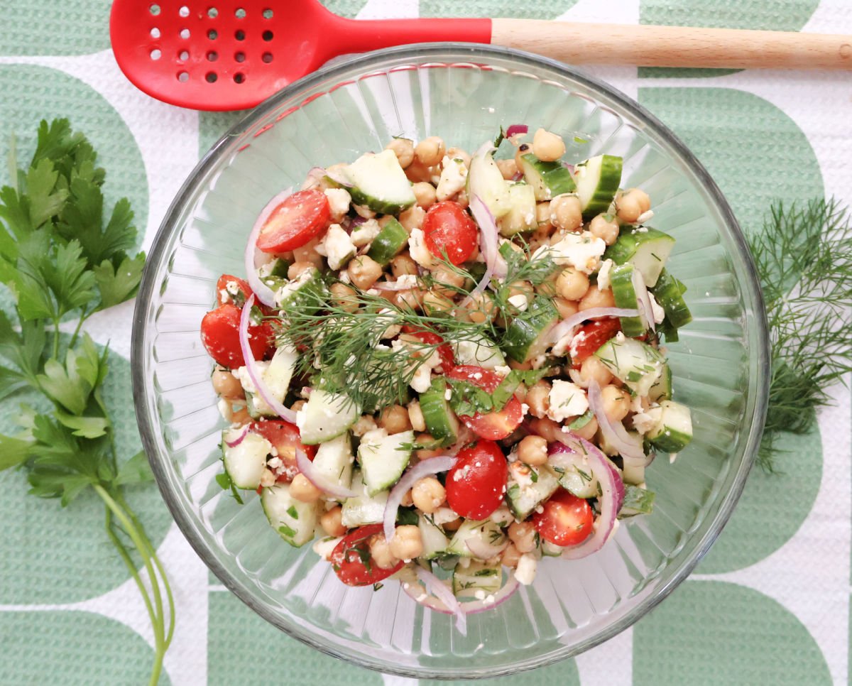Cucumber chickpea salad garnished with fresh dill and parsley sprigs