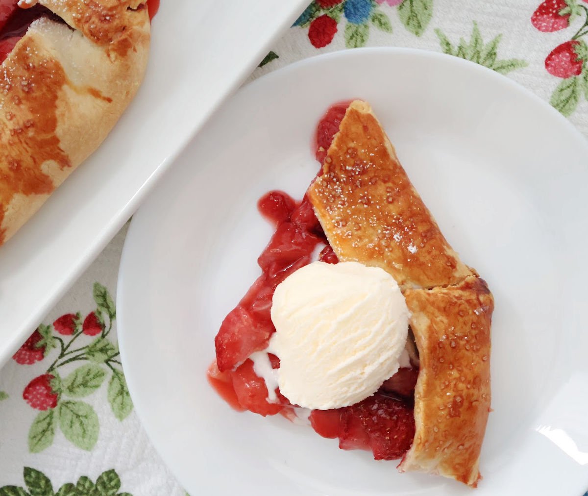 Slice of strawberry galette on a white plate, showing juicy filling