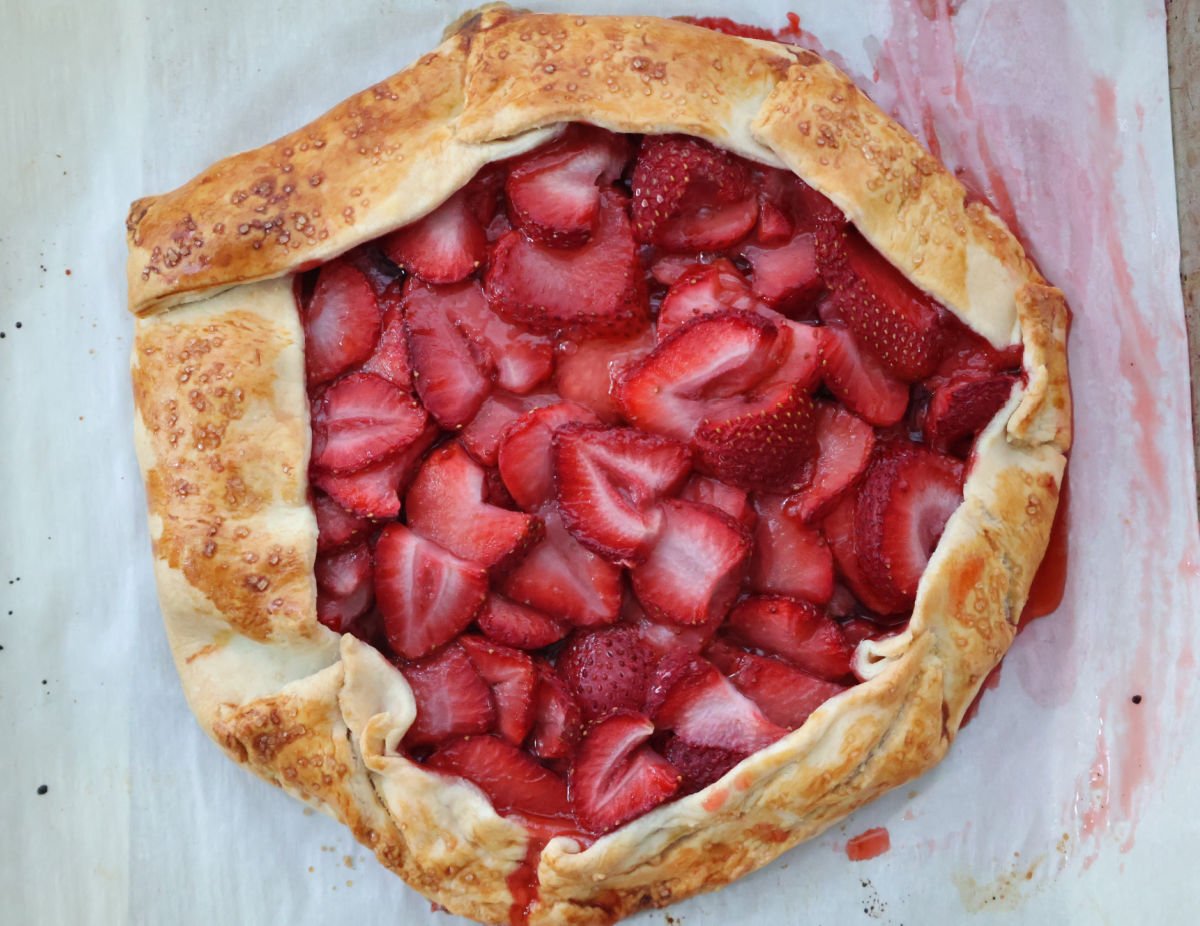 Freshly baked strawberry galette with golden crust on parchment paper.