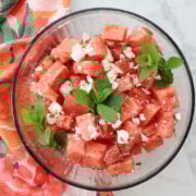 Fresh watermelon feta salad with chopped mint leaves served in a glass bowl.