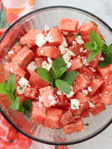 Fresh watermelon feta salad with chopped mint leaves served in a glass bowl.