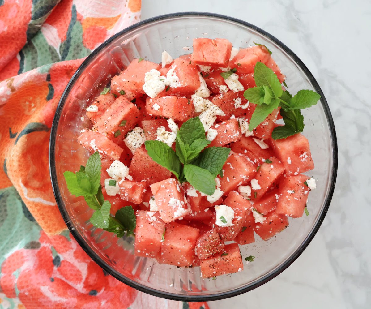 Fresh watermelon feta salad with chopped mint leaves served in a glass bowl.