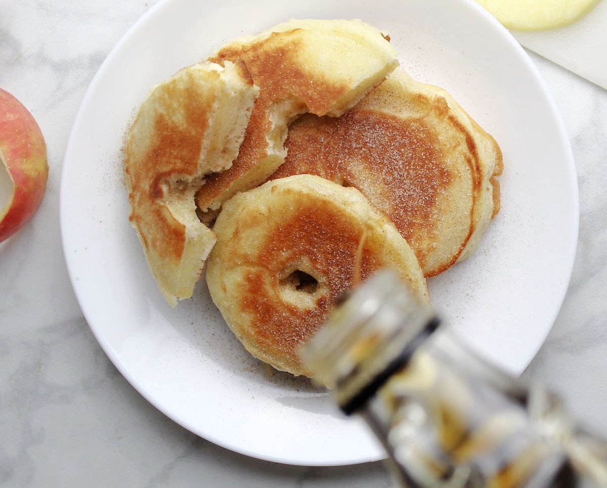 a stack of apple pancake rings with maple syrup poured over them 