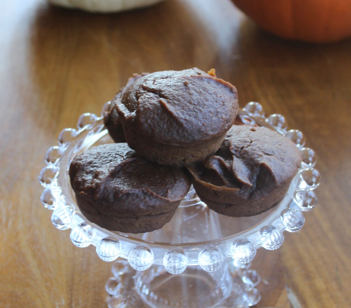 three pumpkin brownie muffins on a glass platter