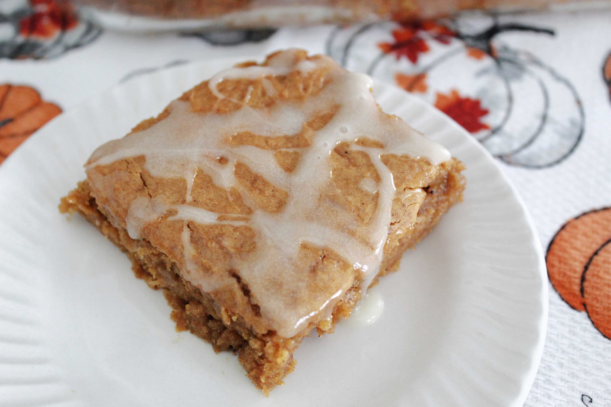 pumpin pudding dump cake with icing drizzle on a white plate.