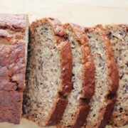 Easy banana bread loaf with several slices on a wooden board, one bowl banana bread recipe.