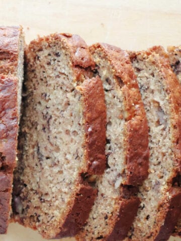 Easy banana bread loaf with several slices on a wooden board, one bowl banana bread recipe.