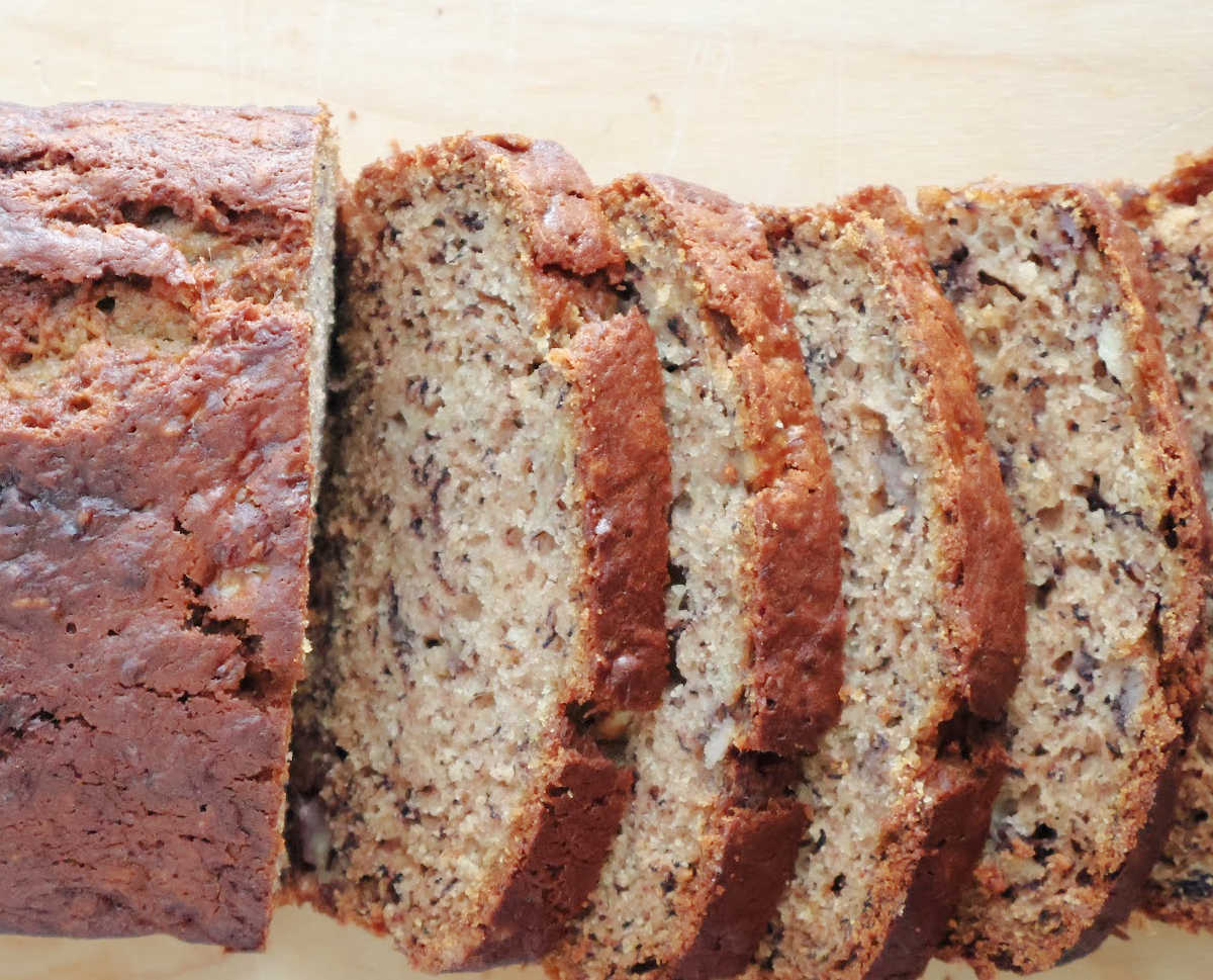 Easy banana bread loaf with several slices on a wooden board, one bowl banana bread recipe.