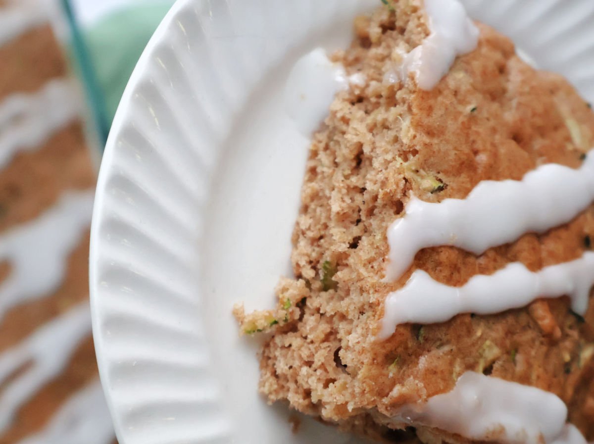 3 ingredient zucchini. a piece with icing glaze on it served on a white plate