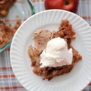 A plate full of Apple Dump Cake made with Spice Cake Mix. Served with a scoop of ice cream.