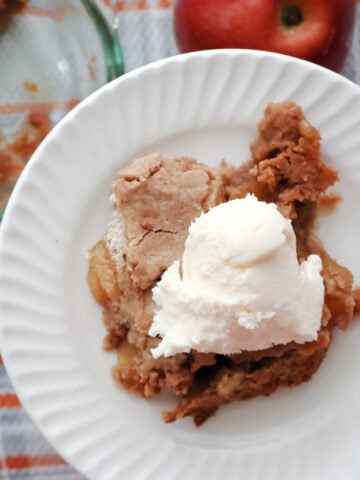 A plate full of Apple Dump Cake made with Spice Cake Mix. Served with a scoop of ice cream.