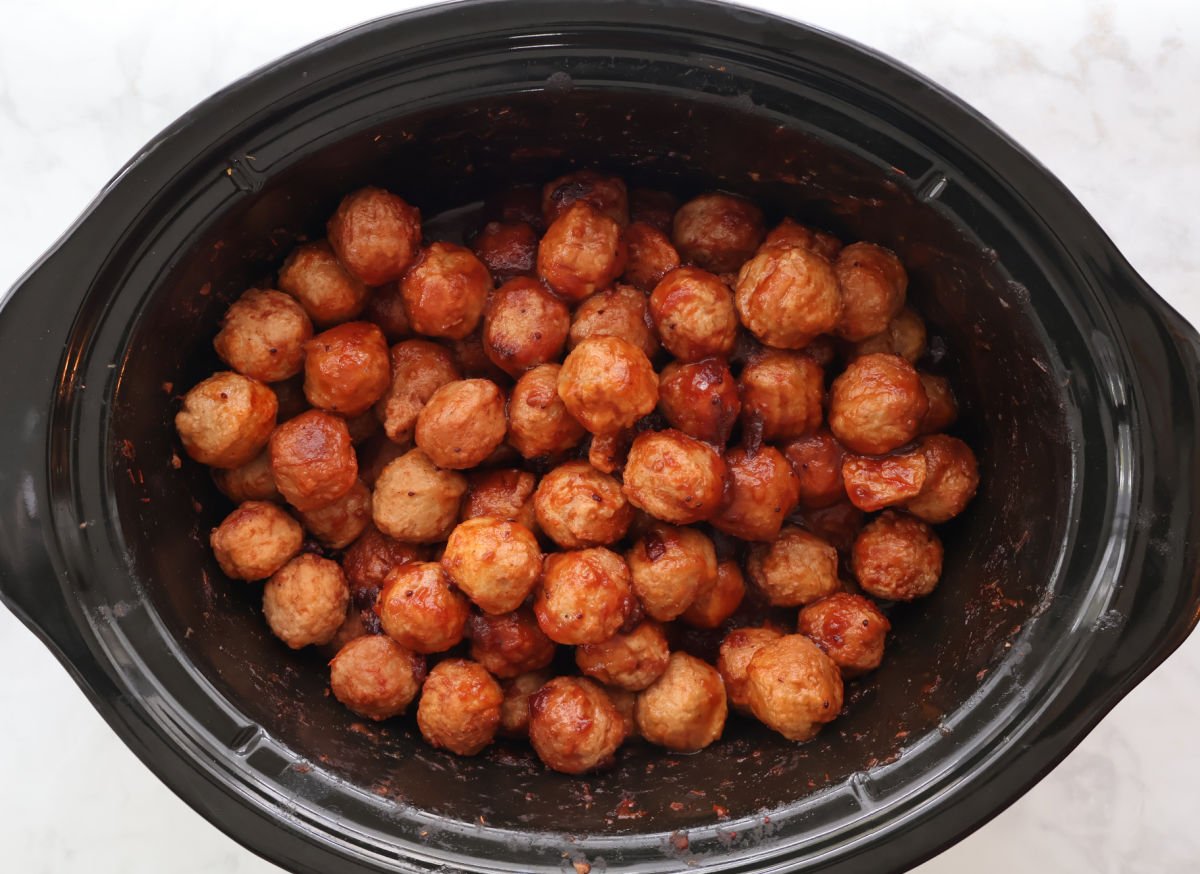 Slow cooker full of cranberry meatballs in a thick, bubbling sauce