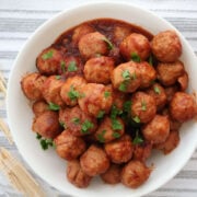 Sweet and tangy cranberry meatballs in a serving dish with toothpicks on the side