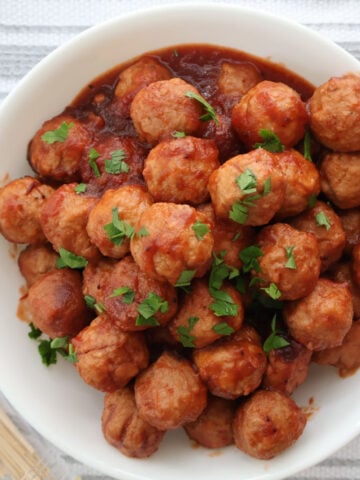 Sweet and tangy cranberry meatballs in a serving dish with toothpicks on the side