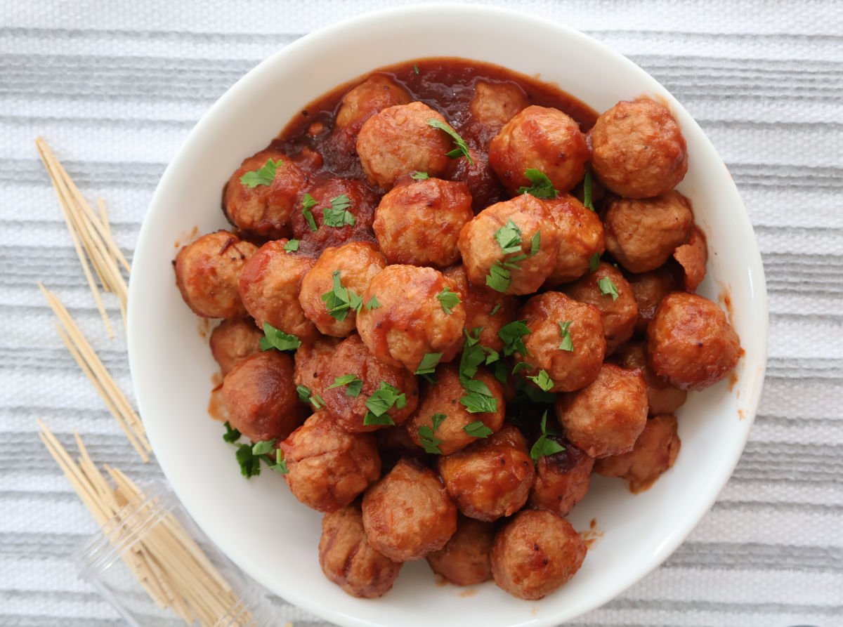 Sweet and tangy cranberry meatballs in a serving dish with toothpicks on the side