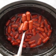 little smokies in a crockpot with grape jelly and chili sauce.