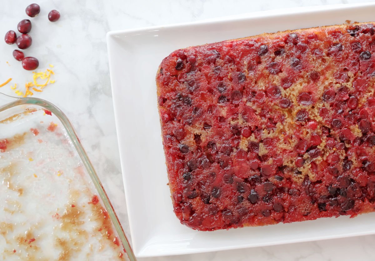 Freshly baked cranberry orange upside down cake turned out onto a platter showing glistening cranberry topping.