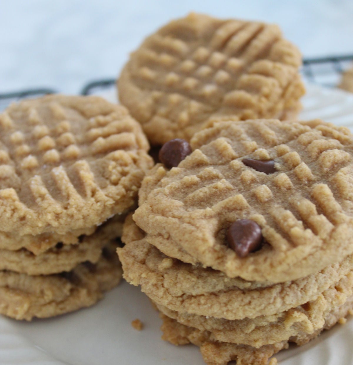 Three piles of 3 ingredient peanut butter cookies. One pile has chocolate chips.