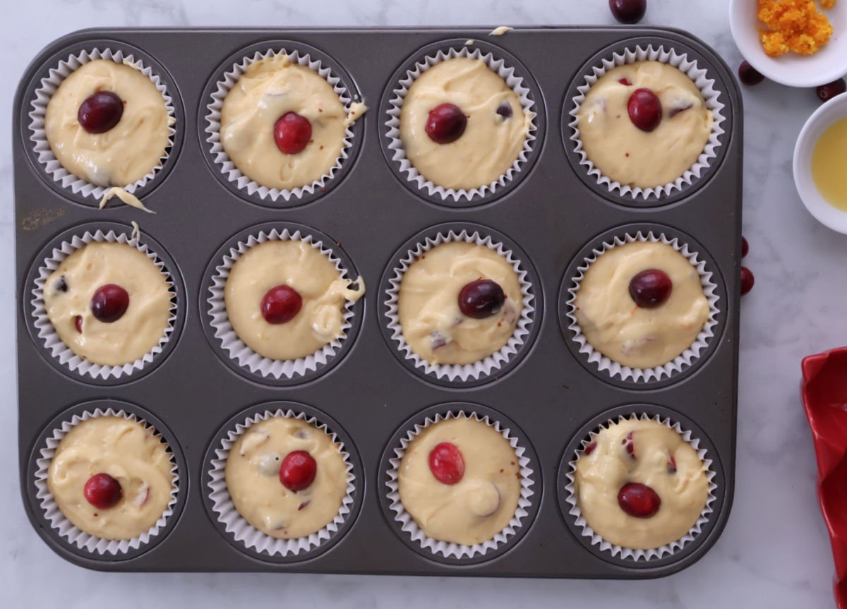 Cranberry orange muffin batter with cranberries on top, ready for the oven. 