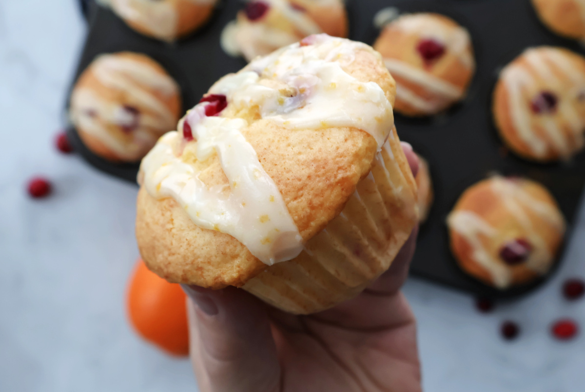 Cranberry orange muffins covered with an orange icing drizzle. 