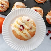 Cranberry orange muffin with orange drizzle. Muffin tin full of muffins in the background.