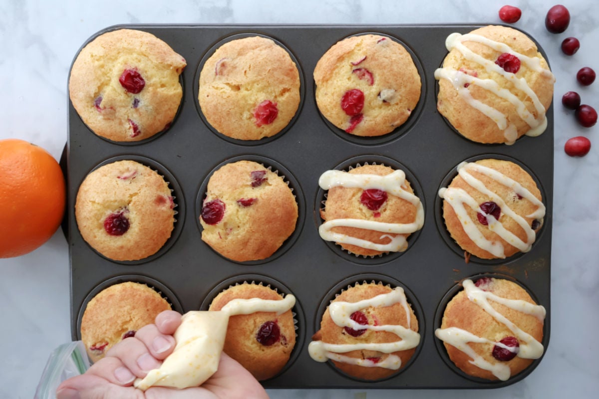 An orange drizzle put onto a dozen baked cranberry orange muffins.